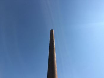 Low angle view of smoke stack against clear blue sky