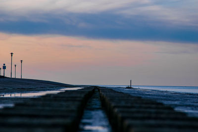 Surface level of pier against sky at sunset
