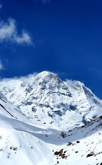 Scenic view of snowcapped mountains against blue sky