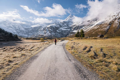 Woman walking on footpath amidst fall colored highland and snow capped mountains in gastein, austria