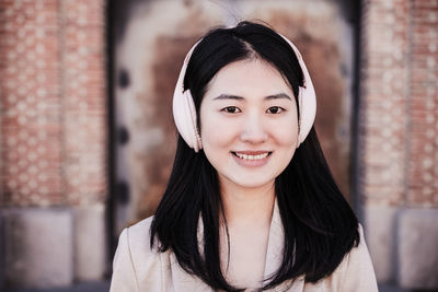 Close up of smiling woman listening to music on headphones and mobile phone in city