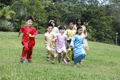 Friends in traditional clothing running on field
