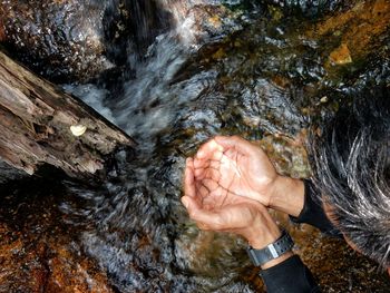 High angle view of man drinking water from stream