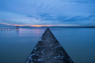 Pier on sea at sunset