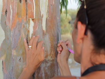 Close-up of woman making heart shape on tree trunk with nail file