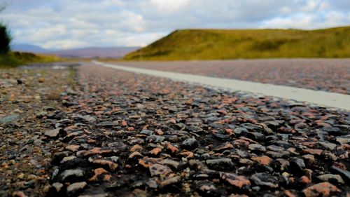 Surface level of pebble road against sky