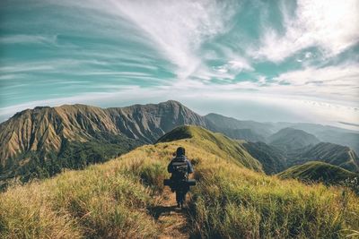 Rear view of man on mountain against sky