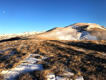 Scenic view of snowcapped mountains against clear blue sky