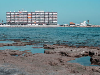 Scenic view of sea by buildings against clear sky