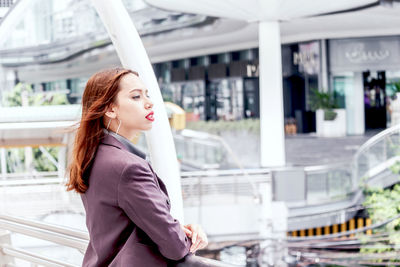 Side view of young businesswoman standing on elevated walkway 