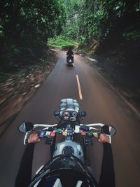 People riding bicycle on road through woods