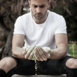 Serious man holding chalk powder while sitting at park