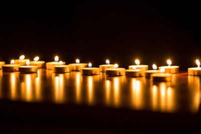 Close-up of illuminated tea light candles over black background