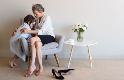 Full length of grandmother with granddaughter sitting on armchair at home