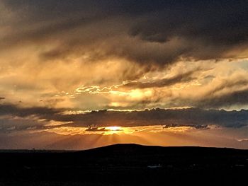 Scenic view of silhouette mountains against dramatic sky
