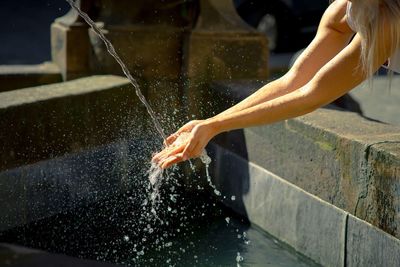 Cropped image of woman washing hands at fountain