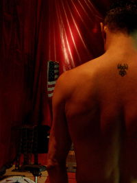 Rear view of shirtless man playing piano