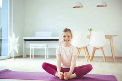 Girl practicing yoga on mat at home
