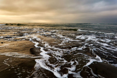 Scenic view of sea against moody sky during sunrise