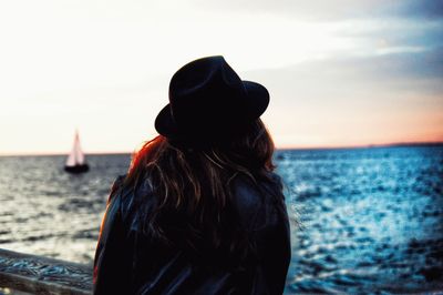 Rear view of woman standing against sea during sunset