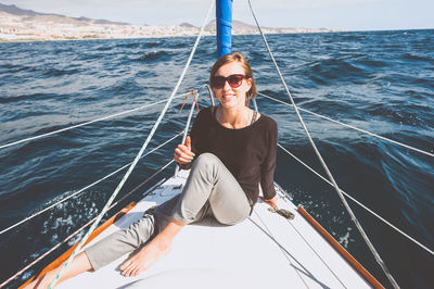 Portrait of smiling young woman sitting in boat on sea