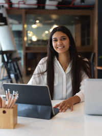 Portrait of smiling businesswoman using laptop at office