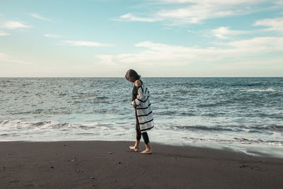 Full length of man standing on beach against sky