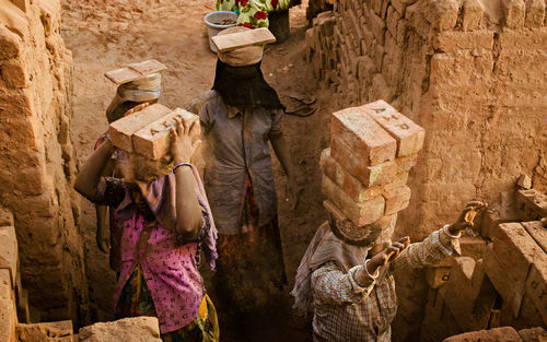 High angle view of manual workers carrying bricks at construction site