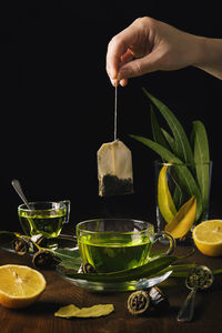 Person puts a bag of herbs in a cup of tea with eucalyptus and lemons