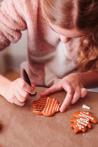 Girl decorating christmas gingerbread cookies at home