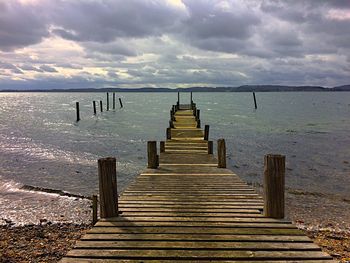 Pier over sea against sky during sunset