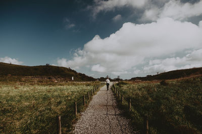 Road amidst field against sky