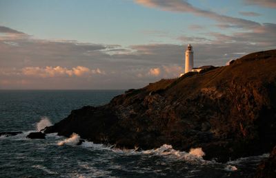 Lighthouse amidst sea and buildings against sky