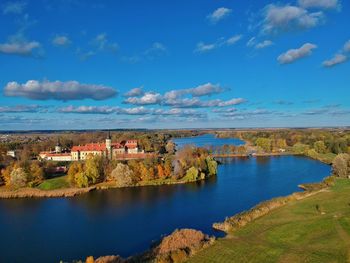 Scenic view of lake and buildings against blue sky