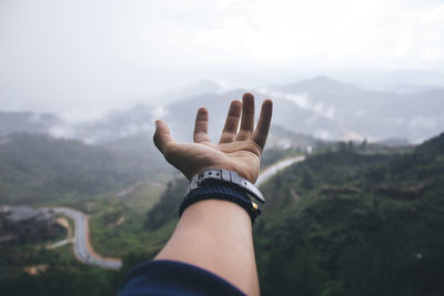 Close-up of human hand against mountain