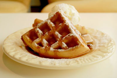 Plate of fresh baked homemade cinnamon apple waffles topped with vanilla ice cream
