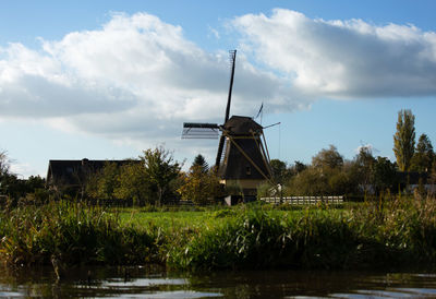 Traditional windmill by trees against sky