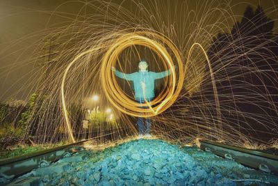 Man spinning wire wool on railroad tacks at night