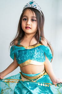 Portrait of a little girl dressed in arabian princess costume against white background.