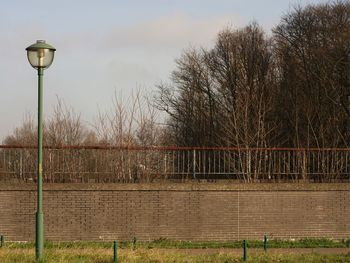 Street by fence against sky