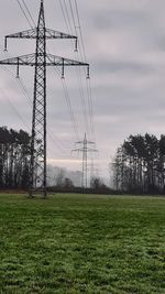 Electricity pylon on field against sky