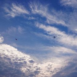 Low angle view of airplane flying against cloudy sky