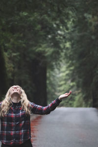 Midsection of woman with arms raised standing outdoors