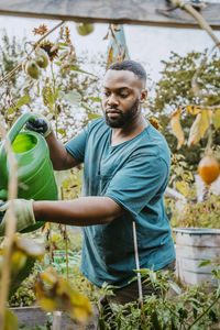 Young male farmer watering plants at urban farm