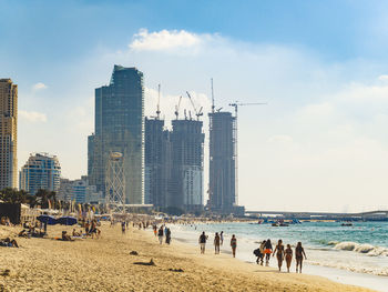 People on beach against buildings in city