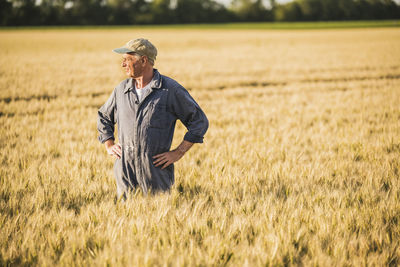 Farmer standing with arms akimbo at wheat field