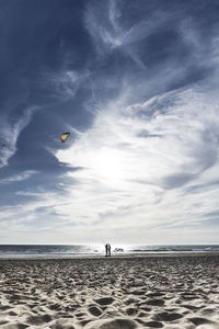 People paragliding on beach against sky