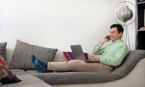 Man using laptop while sitting on sofa at home