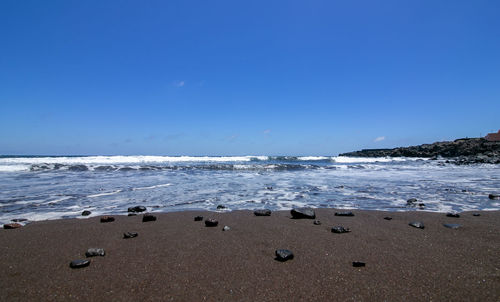 Scenic view of beach against blue sky