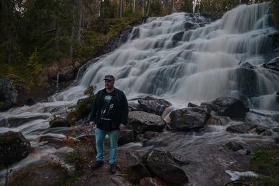 Rear view of man standing against waterfall